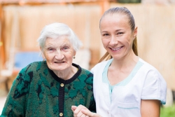 elderly woman with white hair and her caregiver smiling